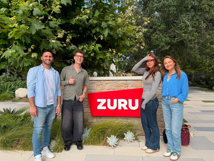 Jeanine with three ZURU colleagues beside the ZURU sign outside the office